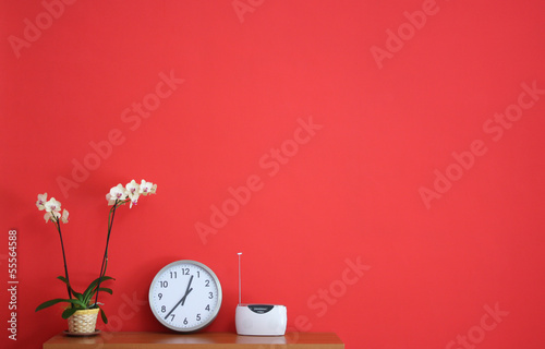 Parete rossa con orchidea e oggetti