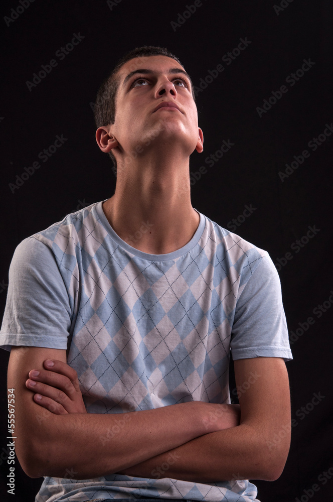 Serious and thoughtful teen boy with hands cross sits on chair