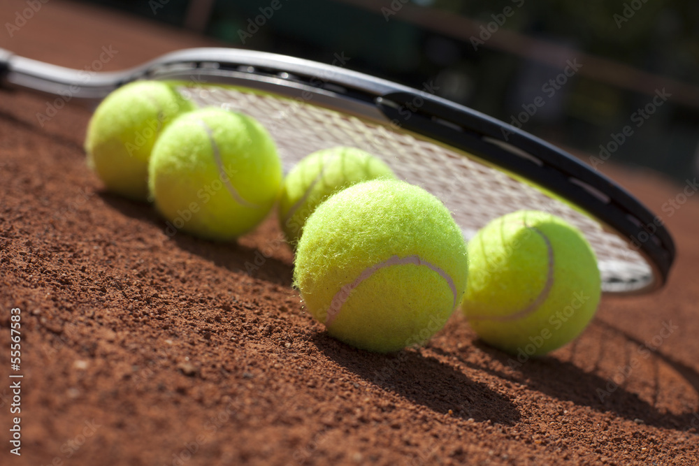 Tennis balls and racket on field