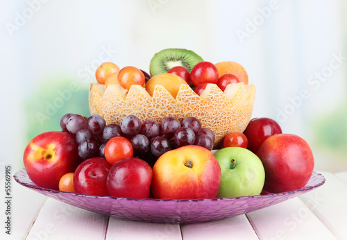 Assortment of juicy fruits on wooden table  on bright