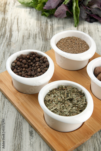 Assortment of spices in white bowls, on wooden background