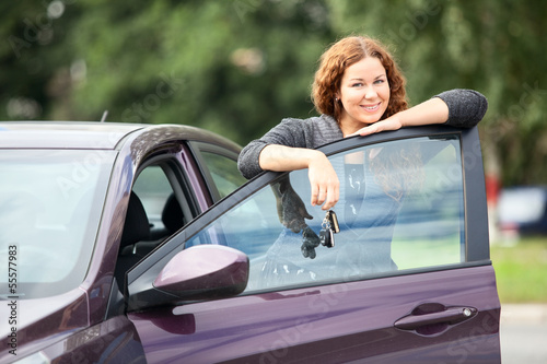 Laughing cheerful woman standing near new car with keys in hand © Kekyalyaynen