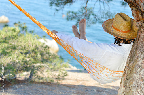 Man in hat in a hammock on pine tree in Crimea a summer day