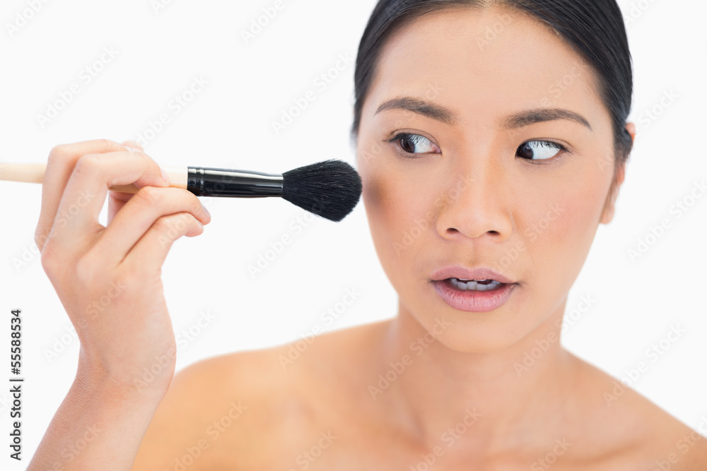 Nervous dark haired model applying powder on her face