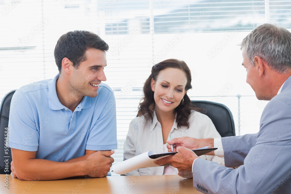Smiling couple signing contract with real estate agent Smiling couple signing contract with real estate agent