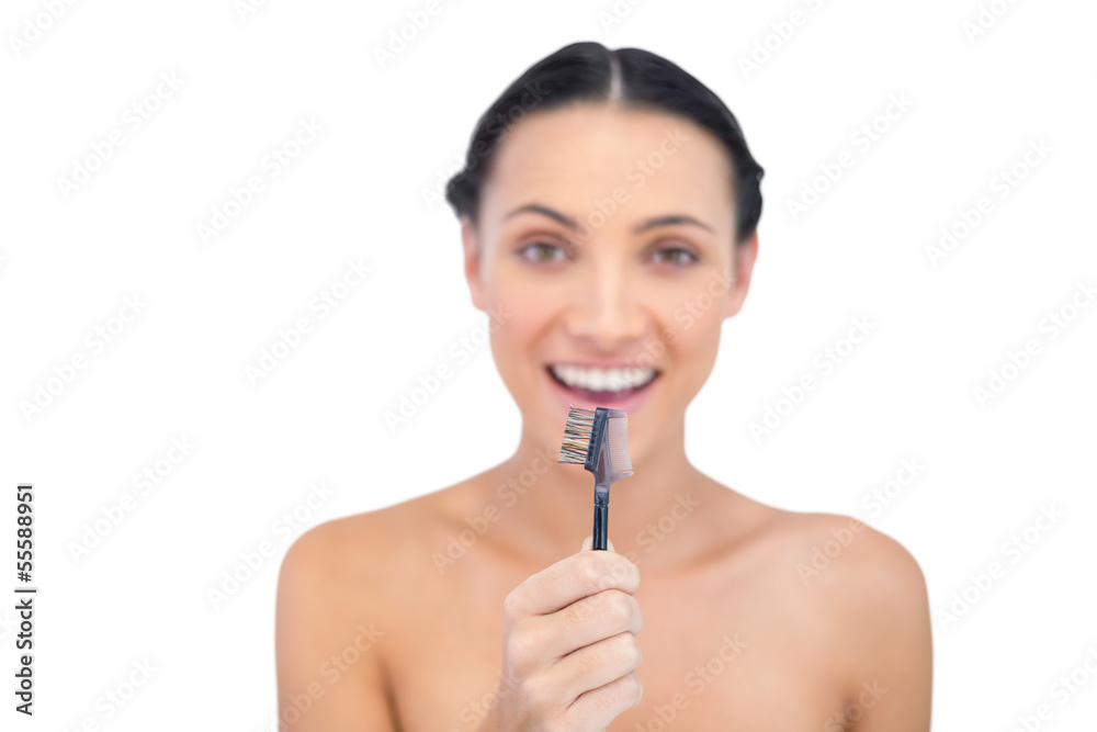 Enthusiastic young model holding eyebrow brush in front of her Enthusiastic young model holding eyebrow brush in front of her