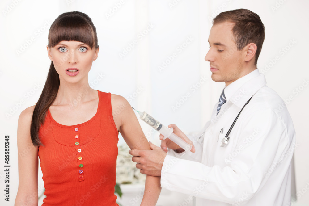 Money injection. Cheerful young male doctor making an injection Money injection. Cheerful young male doctor making an injection