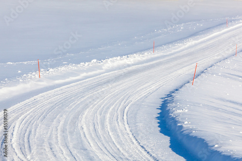 Obraz na plátně Country road with red ploughing marks in the snow