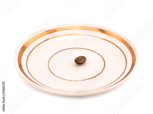 One coffee grain on a white plate.