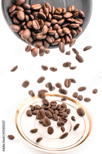 Falling coffee beans, white and black saucer