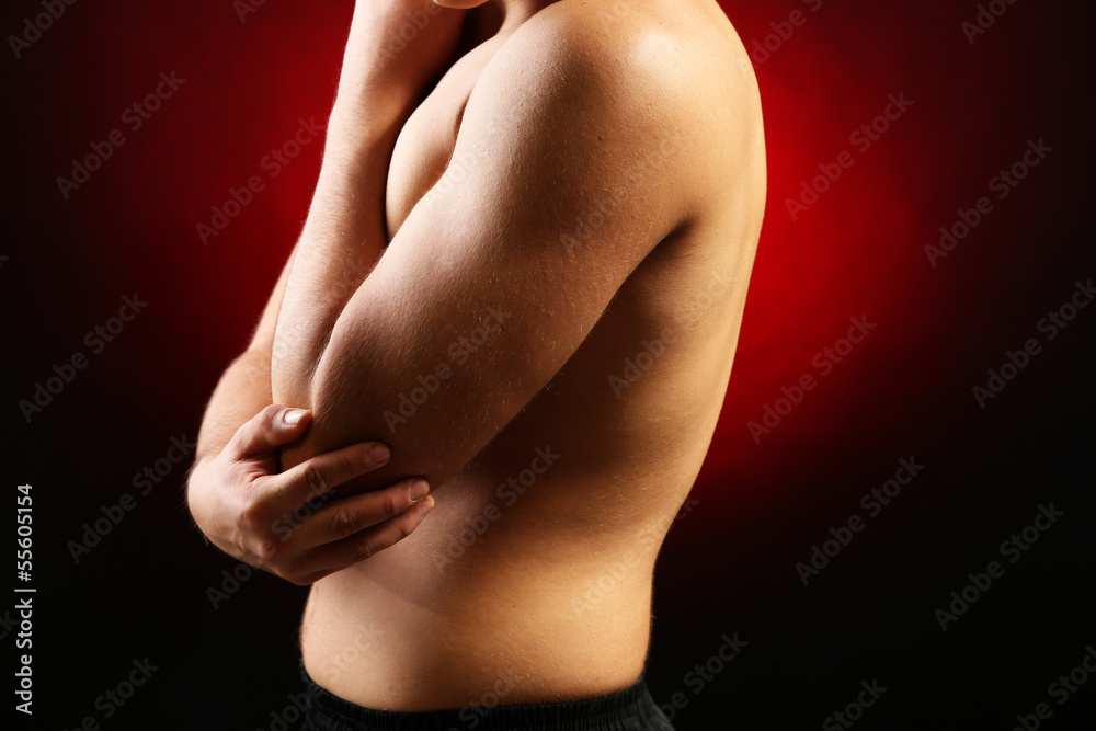 Naklejka premium Young man with elbow pain, on red background