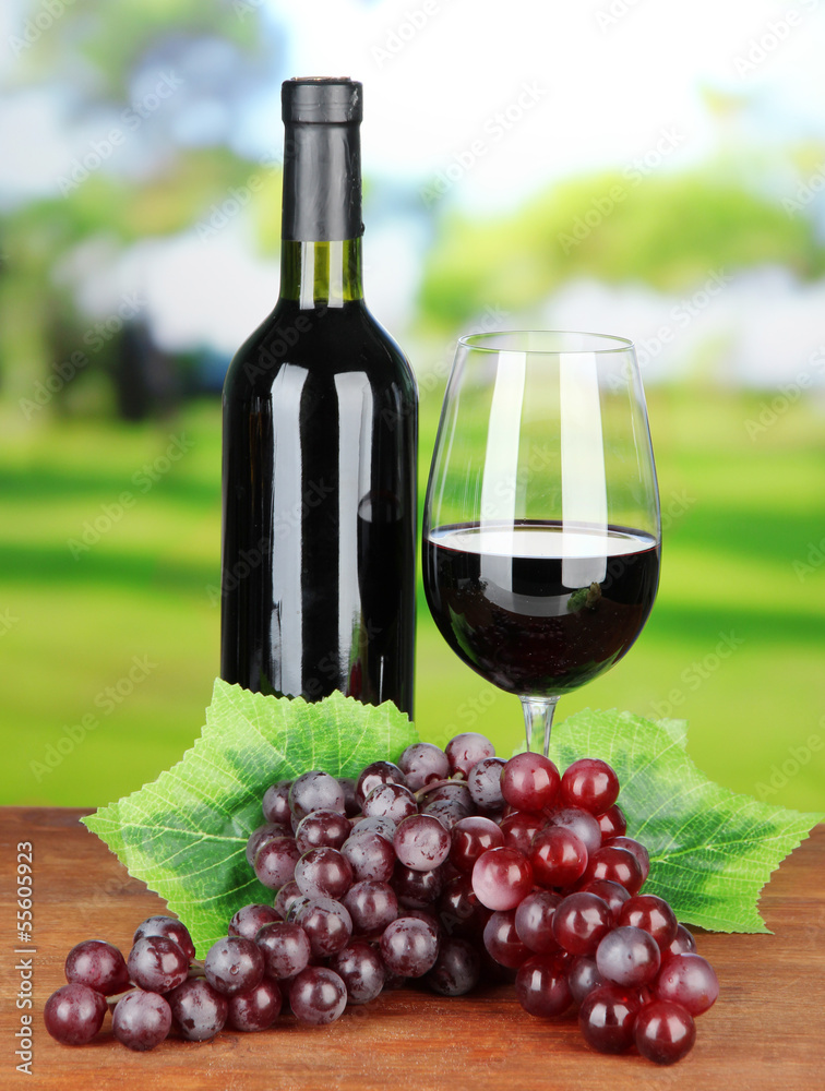 Ripe grapes, bottle and glass of wine on bright background