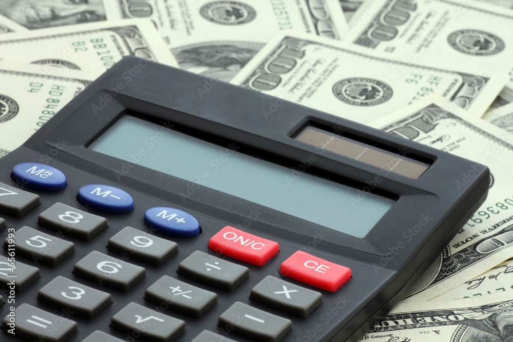 calculator on heap of one hundred dollars banknotes calculator on heap of one hundred dollars banknotes
