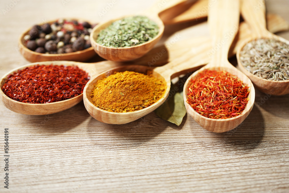 Assortment of spices in wooden spoons on wooden background Assortment of spices in wooden spoons on wooden background