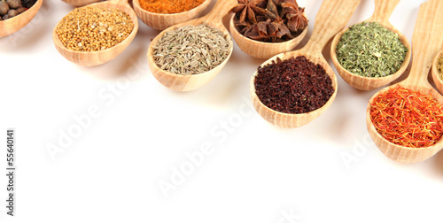 Assortment of spices in wooden spoons  isolated on white
