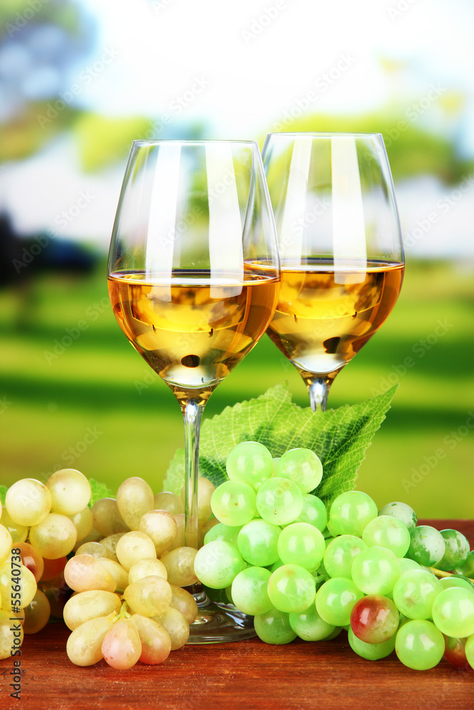 Ripe grapes and glasses of wine, on bright background