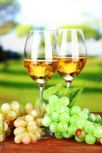 Ripe grapes and glasses of wine  on bright background