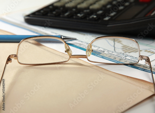 Calculator , folder with paper, pen and glasses