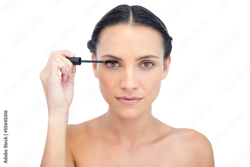 Concentrated young brunette applying mascara Concentrated young brunette applying mascara