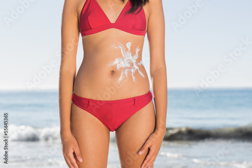 Slim woman body with sun cream on belly