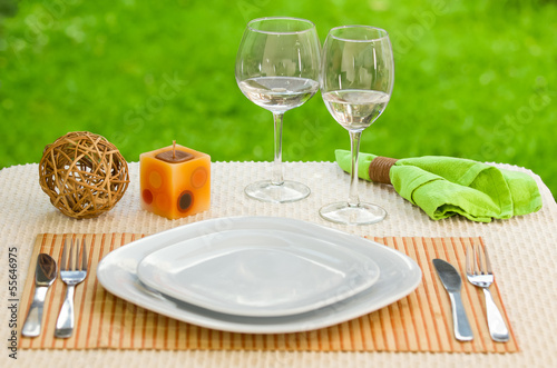 Empty plate with fork and knife against meadow. Table