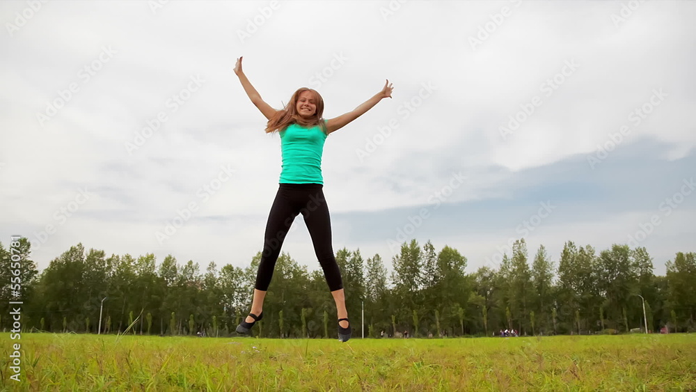 Young woman tumbling wheel, acrobatics on a green glade Young woman tumbling wheel, acrobatics on a green glade