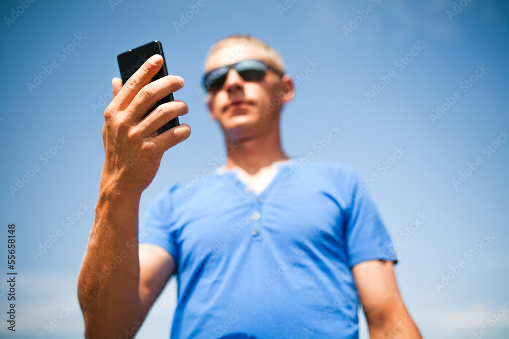 Young man using mobile smart phone, summer outdoor