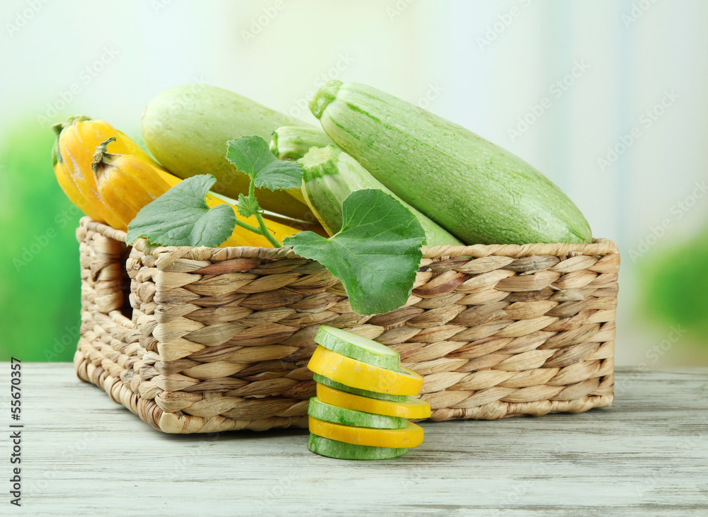 Sliced and whole raw zucchini in wicker crate, outdoors