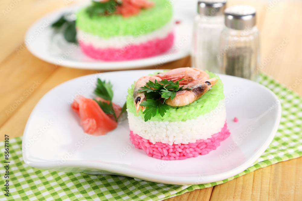 Colored rice on plates on napkin on wooden table Colored rice on plates on napkin on wooden table