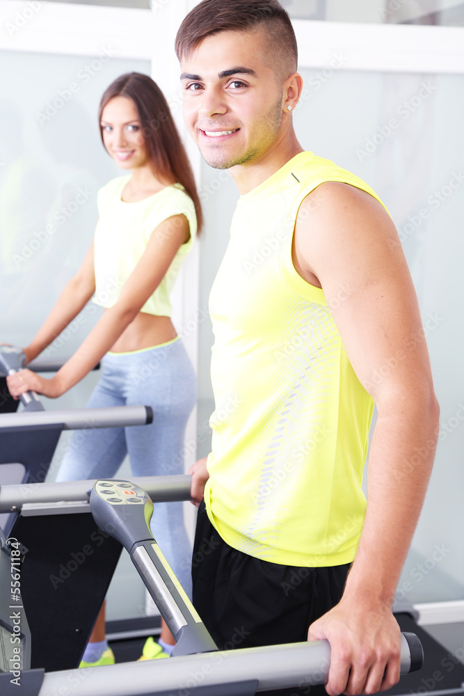 Guy and girl on treadmills at gym Guy and girl on treadmills at gym