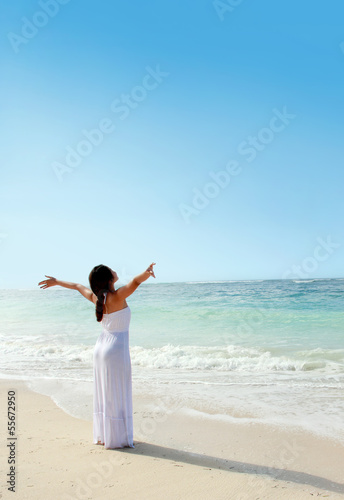 Woman relaxing at the beach with arms open enjoying her freedom