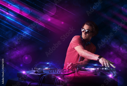 Young DJ playing on turntables with color light effects © ra2 studio
