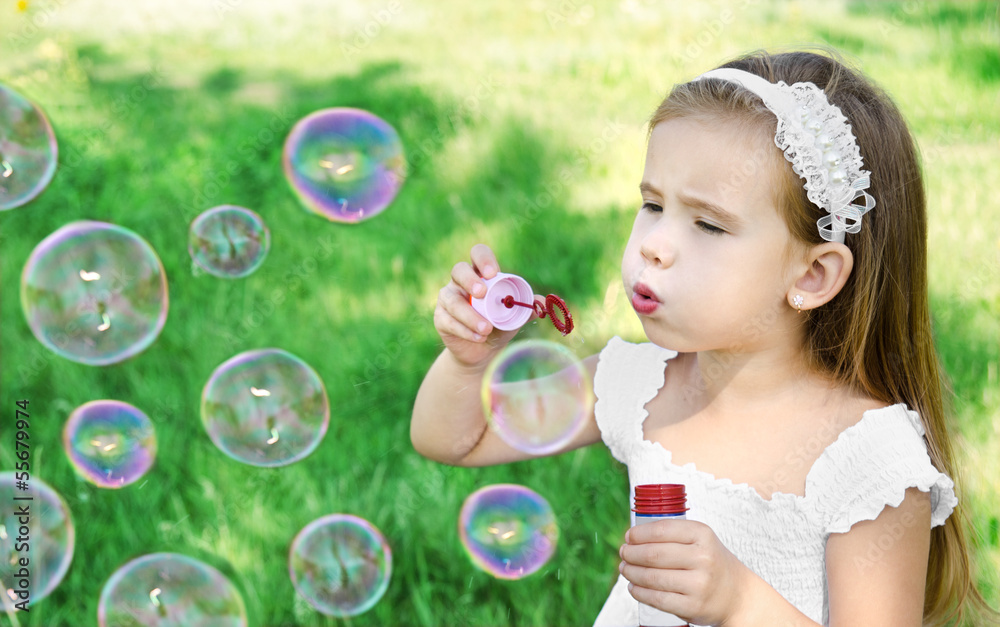 Cute little girl is blowing a soap bubbles