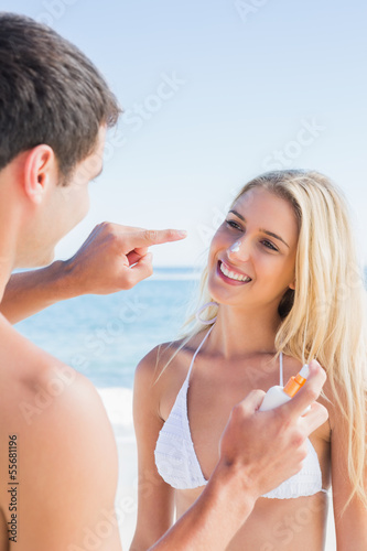 Man putting sun cream on cute girlfriends nose