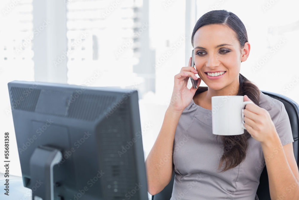 Cheerful attractive businesswoman holding coffee and answering p Cheerful attractive businesswoman holding coffee and answering p