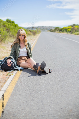 Tired blonde woman sitting on the roadside