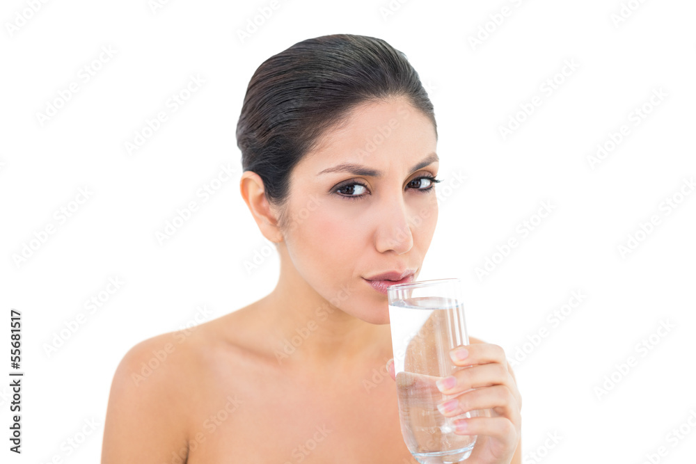 Happy brunette sipping glass of water and looking at camera Happy brunette sipping glass of water and looking at camera
