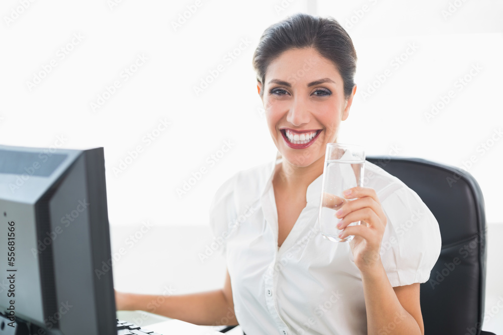 Happy businesswoman holding a glass of water at her desk Happy businesswoman holding a glass of water at her desk