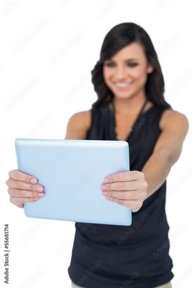 Smiling elegant brown haired model looking at her tablet pc Smiling elegant brown haired model looking at her tablet pc
