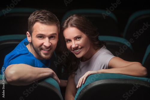 Couple at cinema. Young couple looking over shoulder while sitti