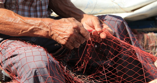 Mani al lavoro su una rete da pesca
