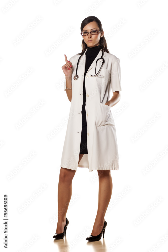 young and serious woman doctor shows a finger upwards young and serious woman doctor shows a finger upwards