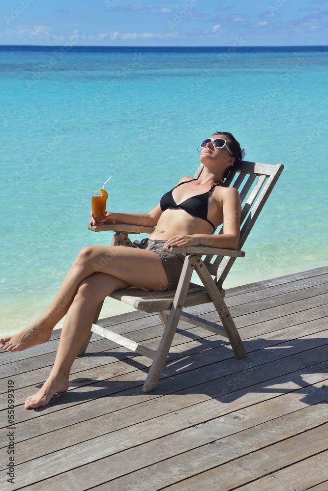 Beautiful young woman with a drink by the sea