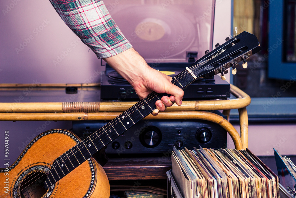 Obraz premium Hand picking up guitar next to box of vinyl