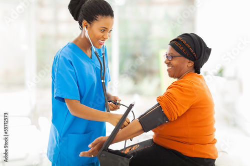 african nurse checking senior patient's blood pressure
