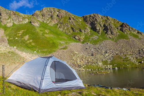 white touristic tent on a mountain lake coast
