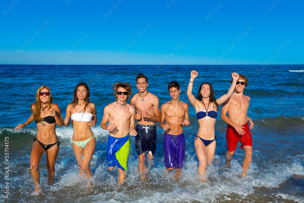 Teens group running happy splashing on the beach Teens group running happy splashing on the beach