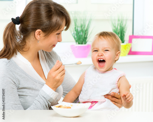 Mother Feeding Her Baby Girl with a Spoon