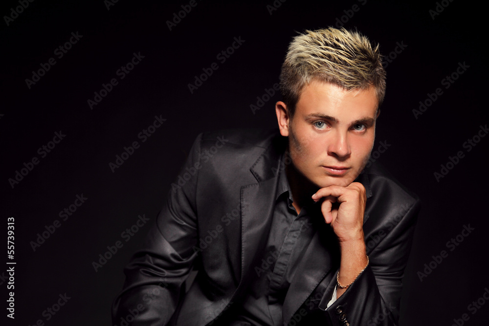 Elegant young handsome man over dark. Studio fashion portrait.