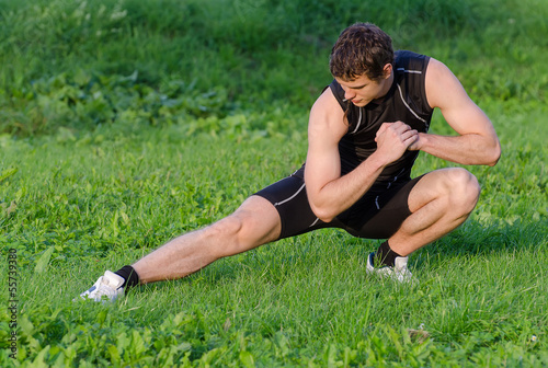 Young sportsman warming up before workout in park